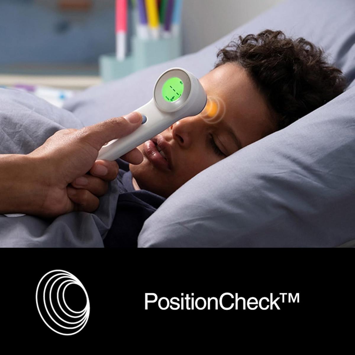 White Braun Sensian 7 non-contact thermometer with green digital display being used on a child's forehead.