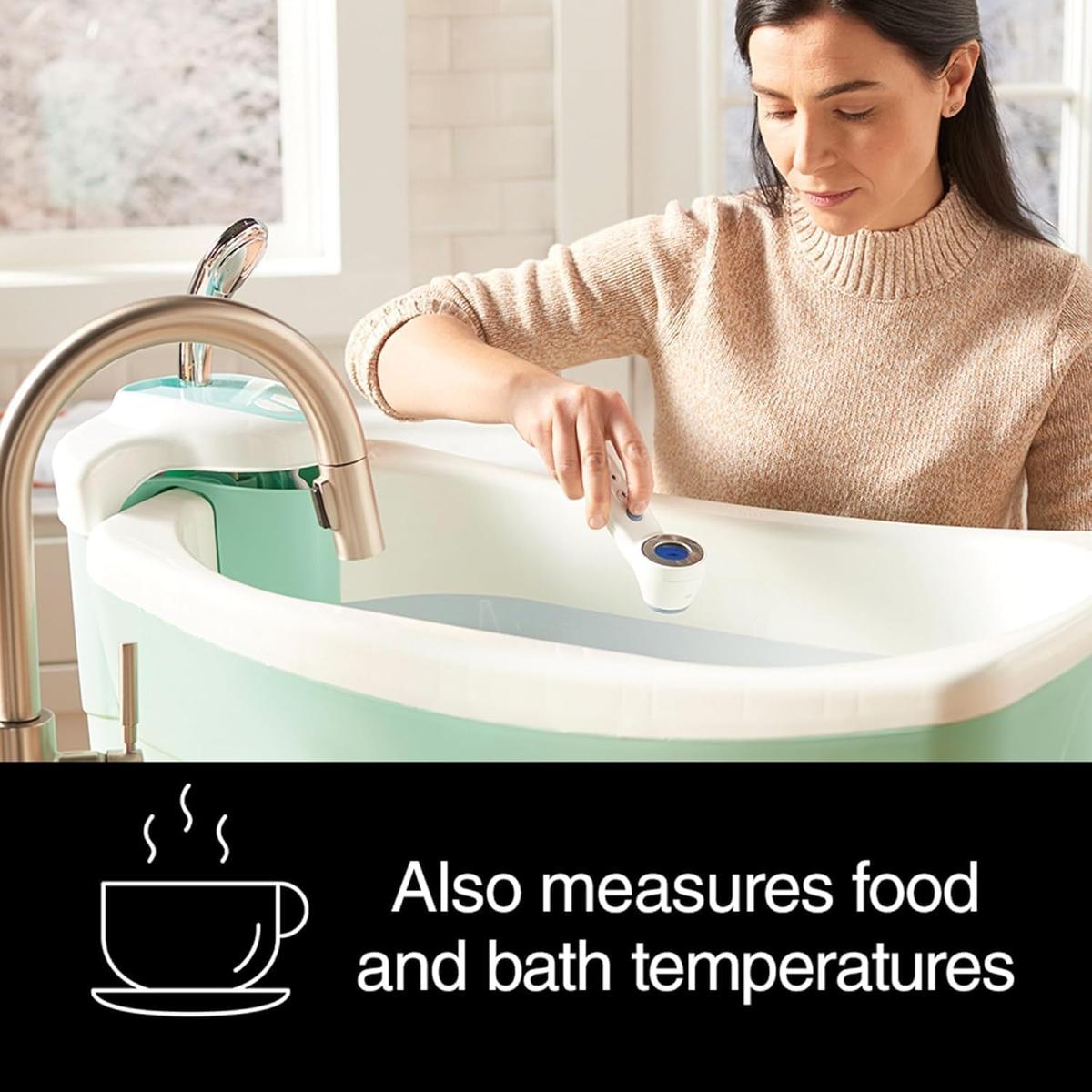 Woman using a white Braun Sensian 7 non-contact thermometer to check the temperature of water in a baby bath.