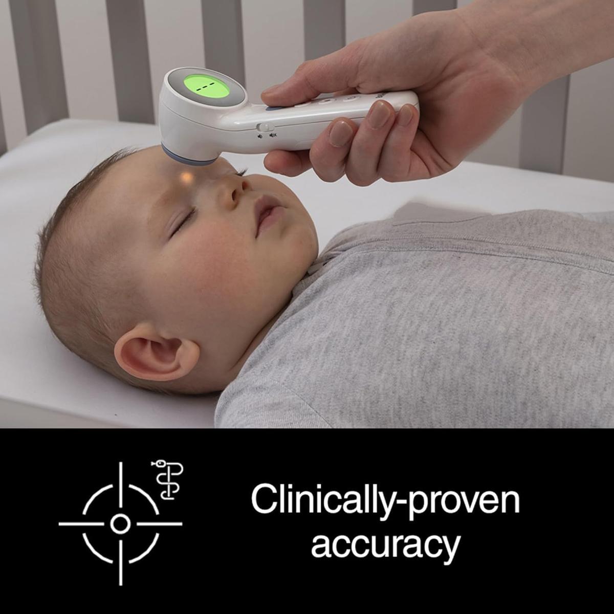 Braun Sensian 7 white non-contact thermometer showing a green display while measuring a baby's forehead temperature.