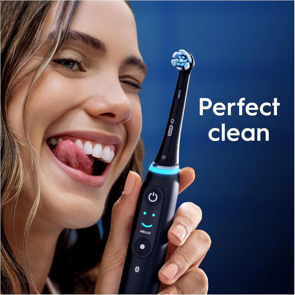 Woman holding a black Oral-B iO electric toothbrush with a round, soft-bristled Gentle Care brush head.