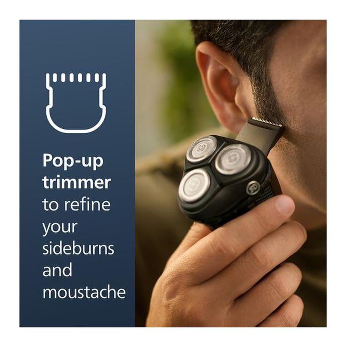 Black Philips Series 3000 electric shaver with pop-up trimmer being used to refine sideburns on a man's face.