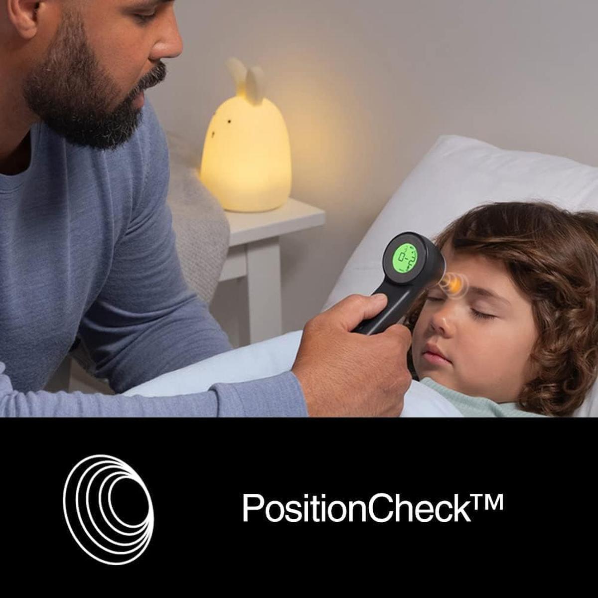 Parent using a black Braun Sensian 7 non-contact thermometer with a green Age Precision display on a sleeping child.