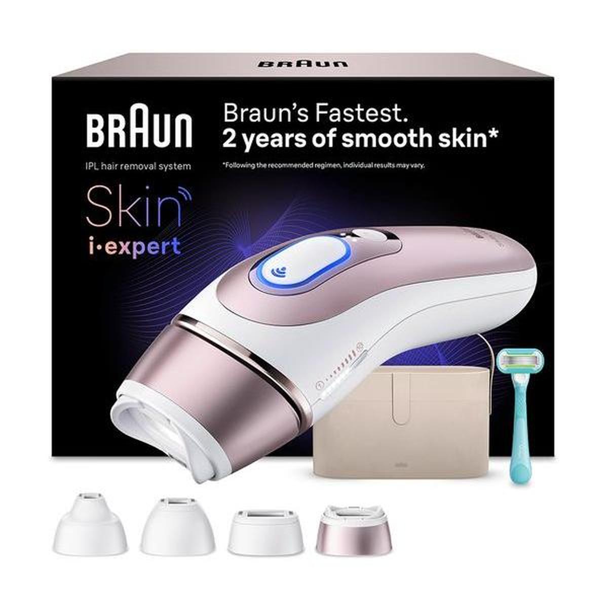 Braun Skin i-expert IPL device in white and rose gold with four attachments, storage pouch, and razor in front of box.
