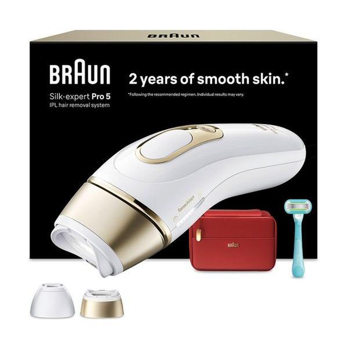 White and gold Braun Silk-expert Pro 5 IPL device with two heads, a red storage case, and a razor in front of its box.