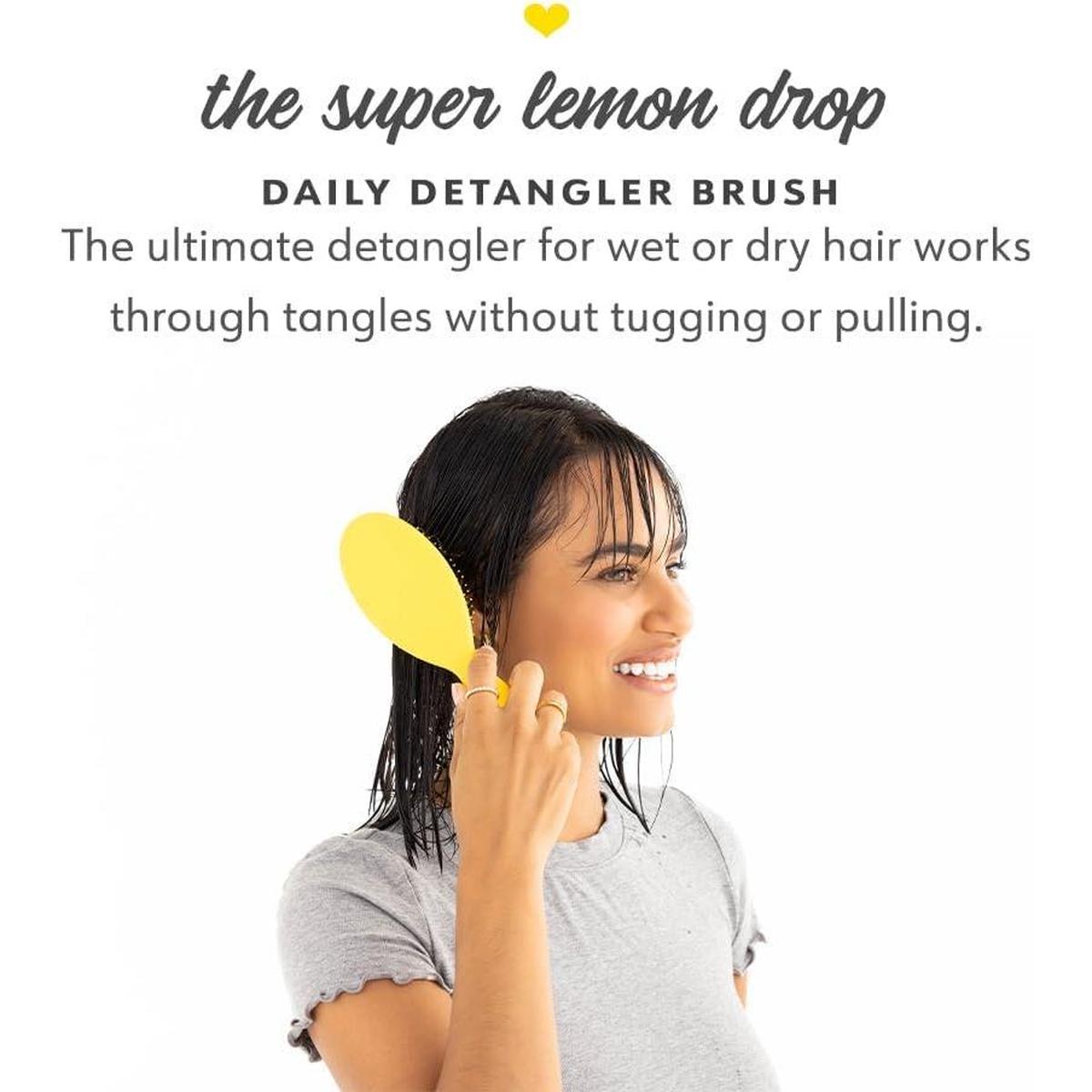 Woman using a bright yellow Drybar Super Lemon Drop detangling brush on her wet hair for smooth, tug-free styling.