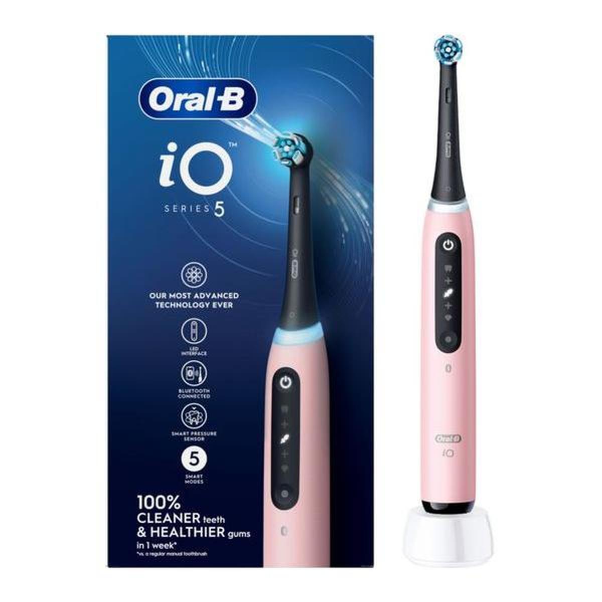 Blush pink Oral-B iO5 electric toothbrush with round brush head, LED interface, and charging base next to its product box.