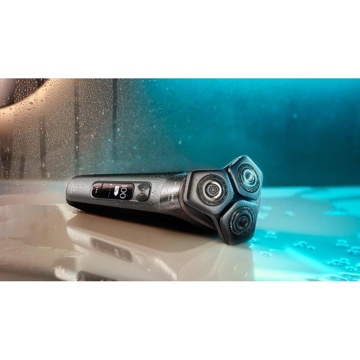 Philips Series 9000 electric shaver with black matte finish, triple rotary heads, and digital display on a wet surface.